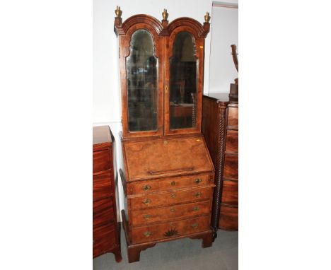 A walnut double dome top bureau bookcase enclosed mirrored doors, fitted one false drawer and three graduated drawers, on bra