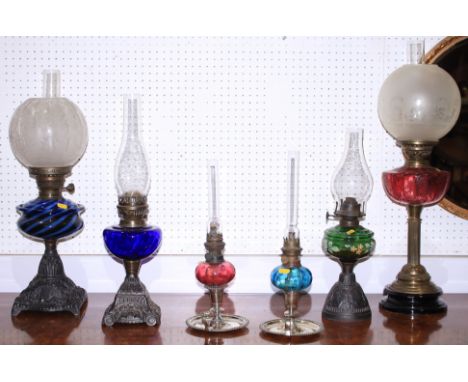 A Victorian oil lamp with etched cranberry glass reservoir and frosted shade, 26 1/2" high, and five other oil lamps