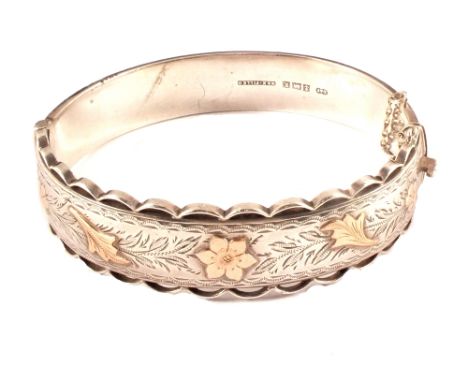 A silver bangle with yellow metal overlay flowers (bangle is wax filled)