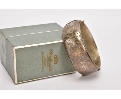 A WIDE SILVER HINGED BANGLE, half of the bangle engraved with a floral and foliate design, push pin integrated box clasp, fit