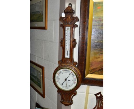 A LATE VICTORIAN OAK CASED ANEROID WHEEL BAROMETER, ceramic scale/dial for the thermometer and barometer, thermometer scale c
