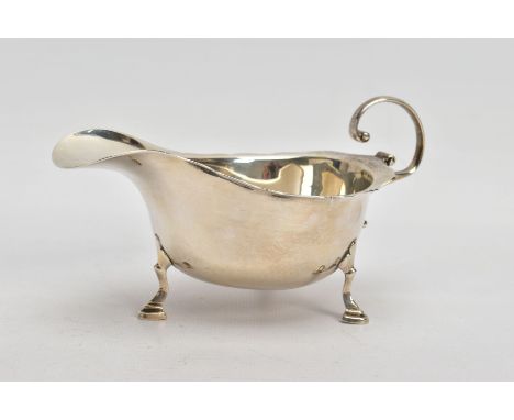 A SILVER 'ASPREY &amp; CO' GRAVY BOAT, plain polished design with a wavy rim, scroll detailed handle, raised on three hoof fe