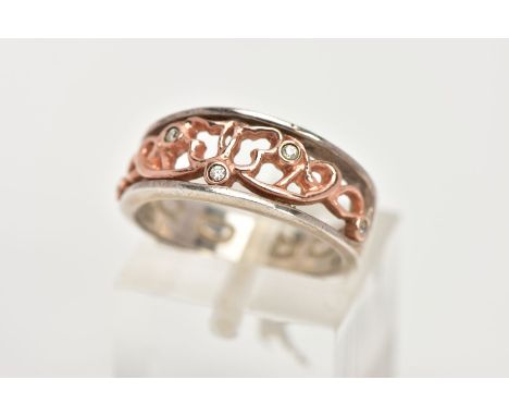 A CLOGAU SILVER AND GOLD RING, designed with a rose gold openwork centre, set with single cut diamond detail, to a plain poli