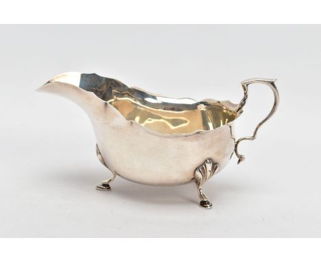 A GEORGE V SILVER GRAVY BOAT, plain polished design, wavy rim, scroll handle, fitted with three hoof feet, hallmarked 'Adie B