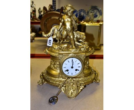 A LATE 19TH CENTURY GILT METAL FIGURAL MANTEL CLOCK, OF OVAL FORM, the surmount cast as a young boy holding fish and nets wit