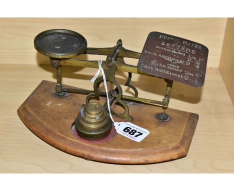 A SET OF POSTAL WEIGHING SCALES WITH A SET OF FIVE WEIGHTS, the gilt metal frame is mounted to a shaped wooden plinth