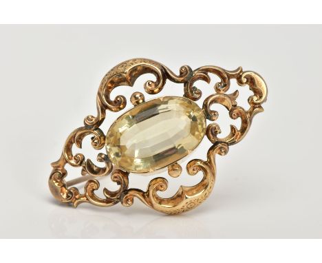 A LATE VICTORIAN GOLD CITRINE BROOCH, the central oval citrine within a scrolling openwork surround, length 53mm, approximate