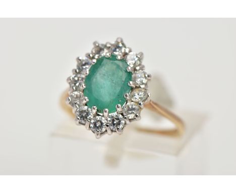 A 9CT GOLD EMERALD AND CUBIC ZIRCONIA CLUSTER RING, designed with a central oval cut emerald, within a surround of colourless