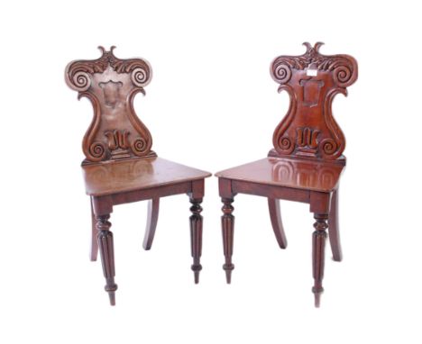 A pair of Victorian 19th century mahogany armorial hall chairs. Each raised on reeded and tapering legs with fitted panel woo