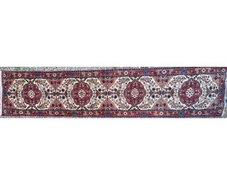 An early 20th century North West Persian Islamic Rudbar hand woven floor runner rug having a series of repeating floral medal