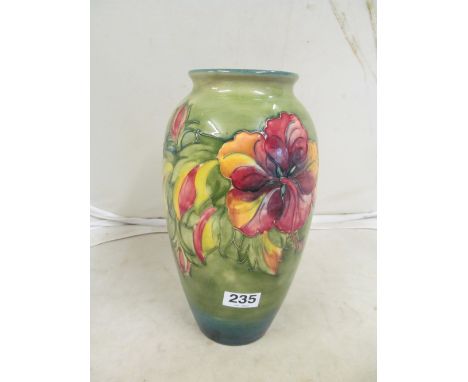 A tall Moorcroft vase hibiscus flowers on green ground