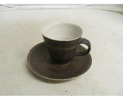 A Lucie Rie cup and saucer with sgraffito linear decoration, mark to base (cup has hairline and saucer five chips to rim)