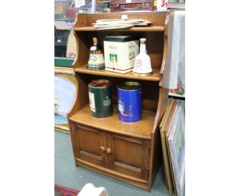 AN ERCOL BOOKCASE UNIT waterfall design, having twin plain panelled cupboard doors to the lower section 