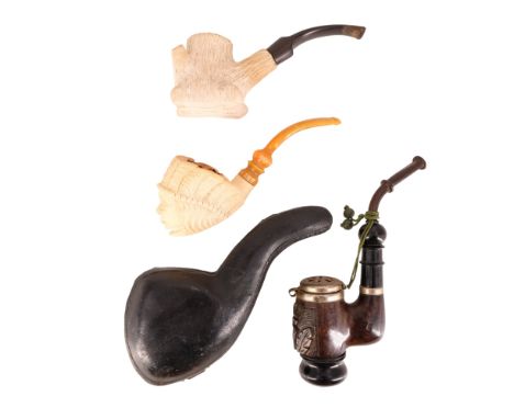 An amber-stemmed meerschaum pipe, its bowl carved in the form of the bust of a Native American, one other meerschaum pipe and