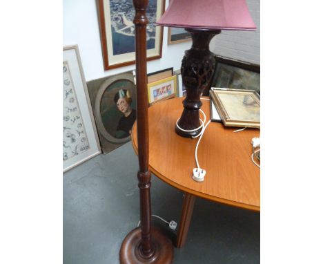 A turned wood standard lamp with a carved Indian style hardwood lamp depicting palm trees and elephants