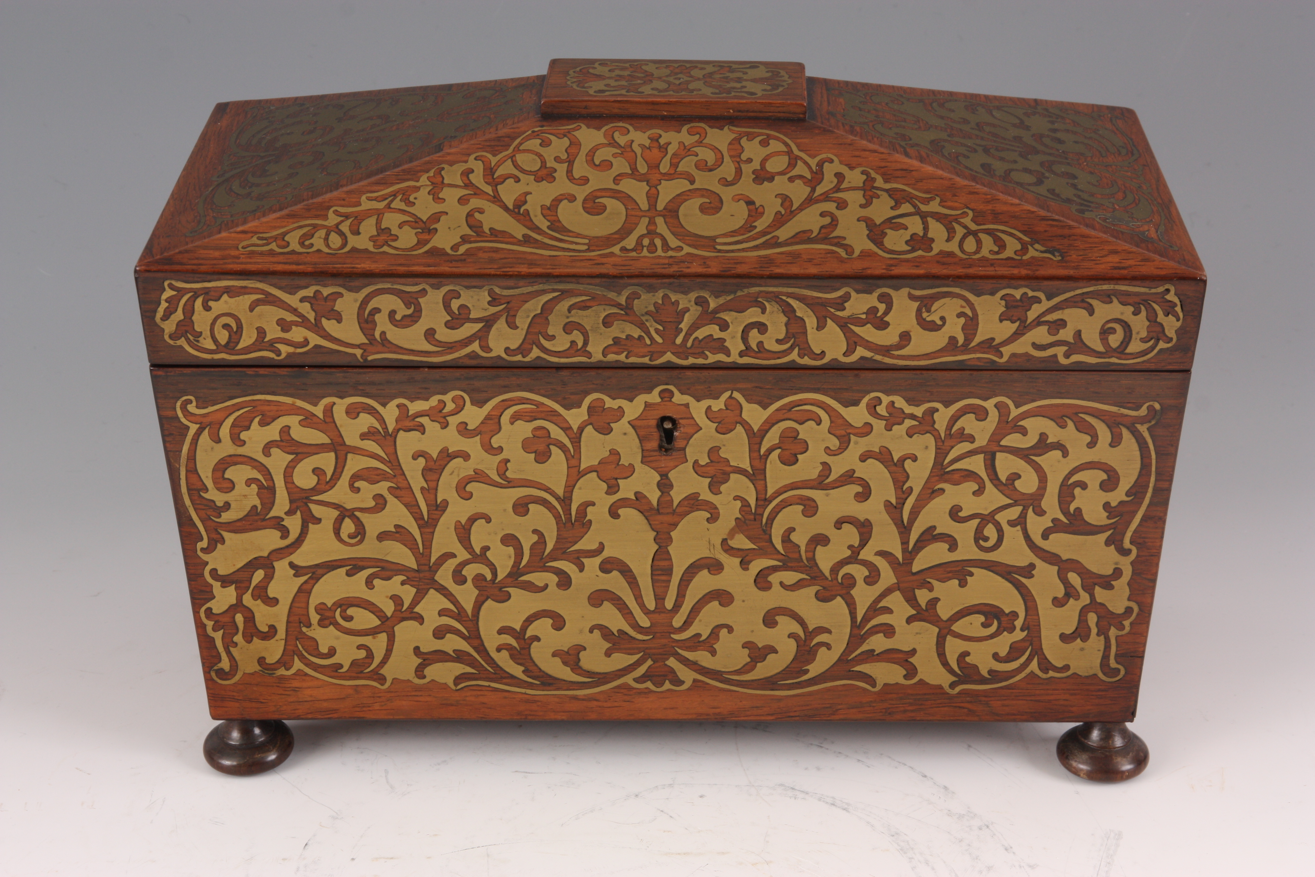 A REGENCY SARCOPHAGUS SHAPED ROSEWOOD AND BRASS INLAID TEA CADDY with a ...