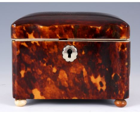 A 19TH CENTURY SMALL SERPENTINE FRONT CONCAVE SIDED RECTANGULAR TORTOISESHELL TEA CADDY with lidded interior raised on small 