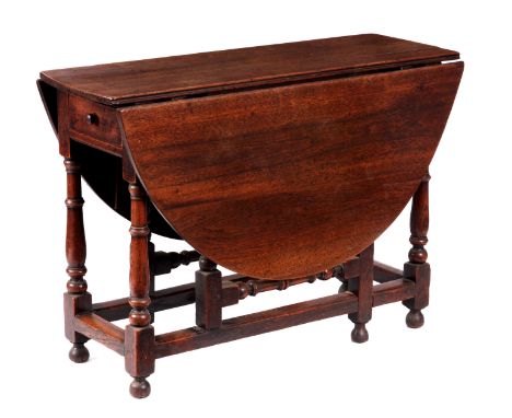 AN EARLY 18TH CENTURY OAK AND WALNUT GATE LEG TABLE with circular drop leaf top above a ring turned base with a fitted frieze