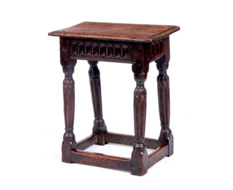 A GOOD EARLY 17TH CENTURY OAK JOINT STOOL the pegged moulded edge top above a gouge carved frieze and fluted slender turned t