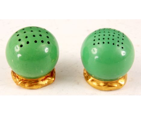 A ROYAL WORCESTER CIRCULAR GREEN SALT AND PEPPER CONDIMENT SET having pierced tops and gilt moulded bases; the underneath wit