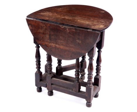 A MID 18TH CENTURY SMALL OAK GATE LEG TABLE with oval drop leaf top above a turned leg base frieze drawer and joined by botto