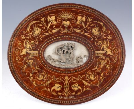 AN EDWARDIAN CARVED CERAMIC OVAL PLAQUE depicting cupids playing with two young females, set in a mahogany oval inlaid frame 
