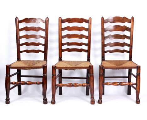 A SET OF SIX 19TH CENTURY ELM LADDER BACK DINING CHAIRS with rushed seats turned legs and joined by stretchers.