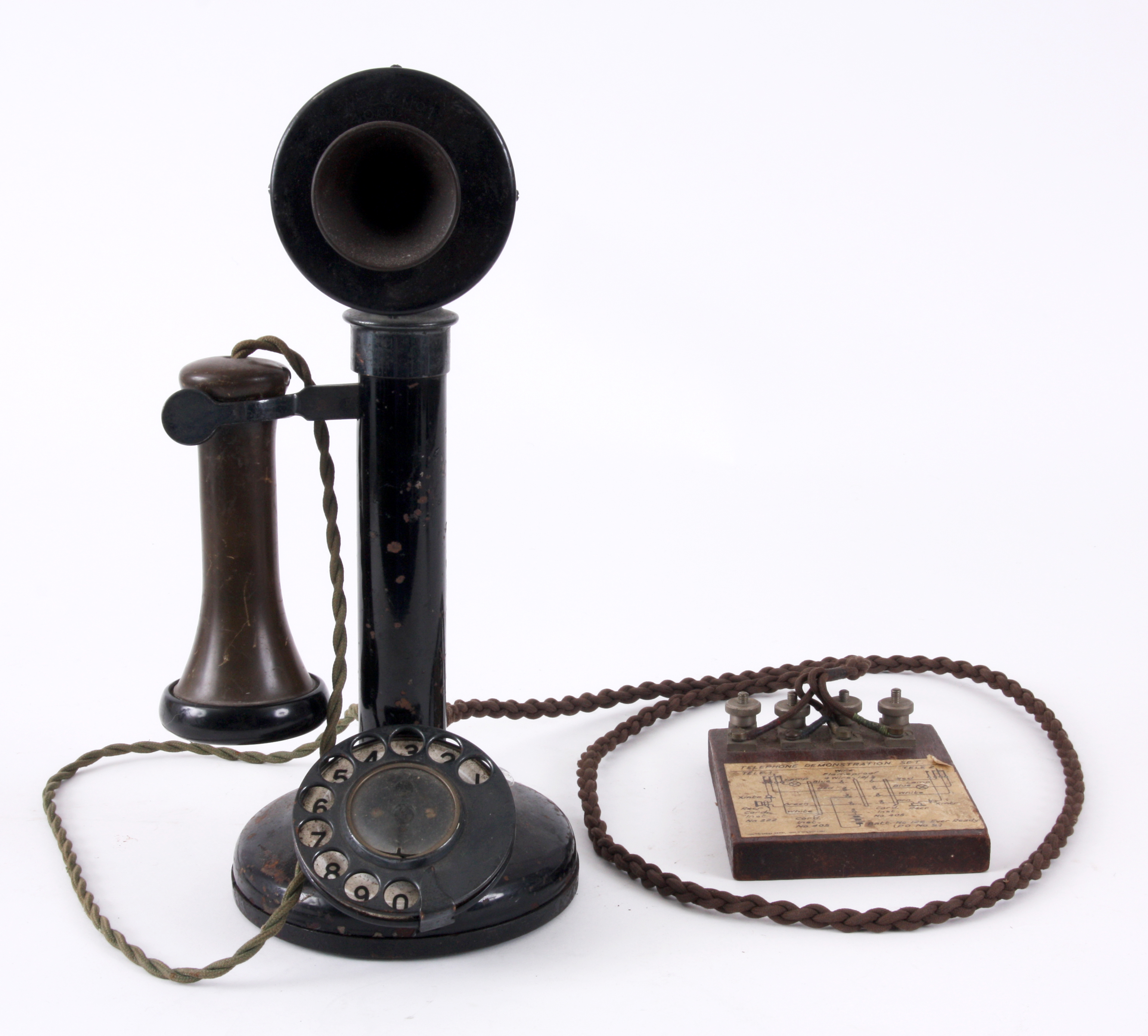 AN EARLY CANDLESTICK TELEPHONE with enamelled number dial and bakelite earpiece, the base with bu