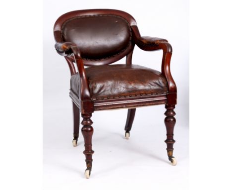 A 19TH CENTURY IRISH CAMPAIGNE ARMCHAIR with oval studded leather back and seat joined by shaped arms; standing on ring turne