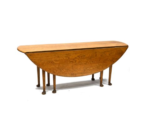 A 20th Century reproduction of a Georgian style wake table in mid oak, supported on eight legs with pad feet. Extending with 