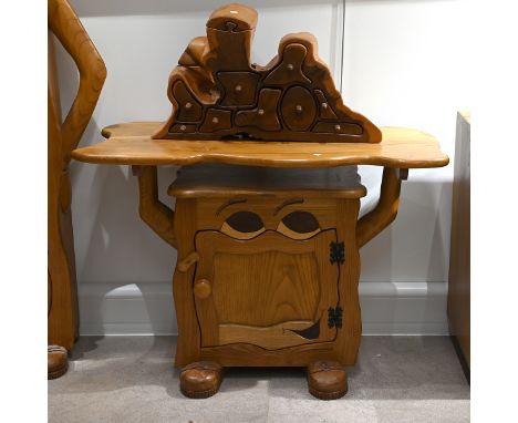 A late 20th century carved oak character side table with cabinet under. The cabinet having carved eyes, arms and booted feet,