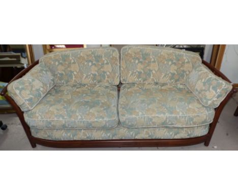 A modern Ercol elm framed 3 seater settee with slat back, the loose cushions and seat in green floral tapestry