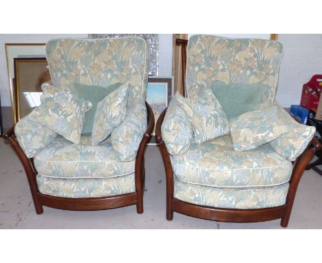 A pair of Ercol high back armchairs upholstered in green floral tapestry