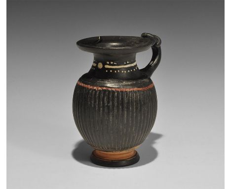 5th-3rd century BC. A Gnathian ceramic blackware juglet with pedestal base, ribbed bulbous body, waisted neck and everted rim