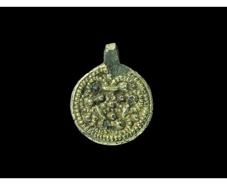 10th-12th century AD. A discoid silver-gilt pendant with integral loop, trefoil of pellets and granules within a pelletted bo