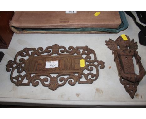A cast iron welcome home sign together with a door knocker decorated with a cherub