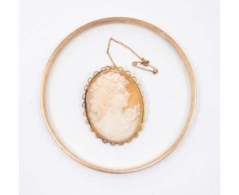 A yellow metal, metal core bangle and a mid 20th century cameo brooch. The bangle is stamped "9ct Metal Core" and has an inte
