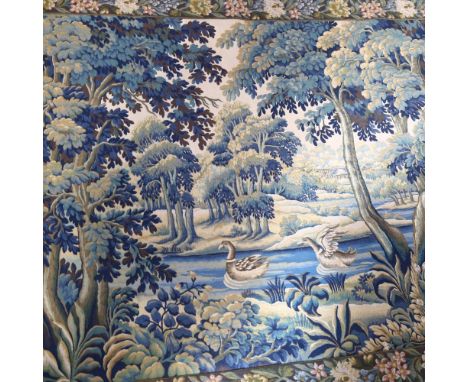 A machine woven, possibly French, tapestry depicting a woodland or landscape scene, with ducks swimming in the river, buildin