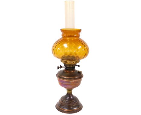 An early 20thC copper oil lamp, with a glass chimney and fluted amber glass shade, 59cm high. 