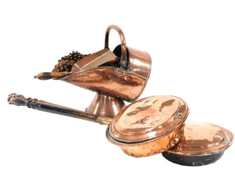 A Victorian copper helmet shaped coal scuttle, with shovel, together with two copper bed pans, with turned wooden handles.