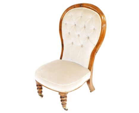 A Victorian balloon back nursing chair, upholstered in light brown button back draylon, raised on turned legs, brass capped o
