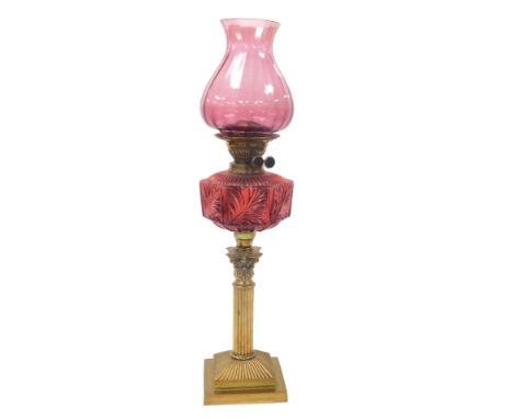 A late 19thC brass Corinthian column oil lamp, with a ruby glass reservoir, and an amethyst glass shade, 64cm high.