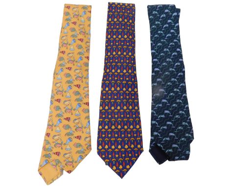 Three Hermes silk ties, comprising a yellow tie with hats, dark blue tie with trees, and a dark blue tie with dolphins.