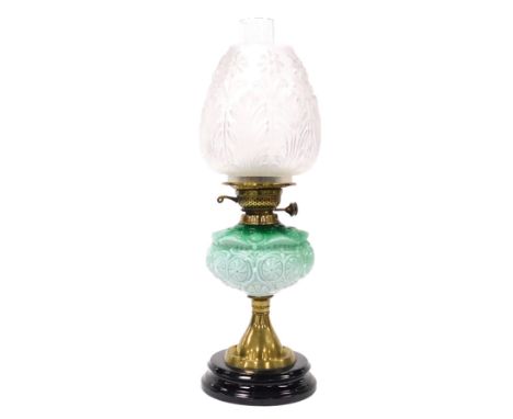A late 19thC brass oil lamp, with a pale green and white opaline reservoir, moulded with flower heads and leaves, with chimne