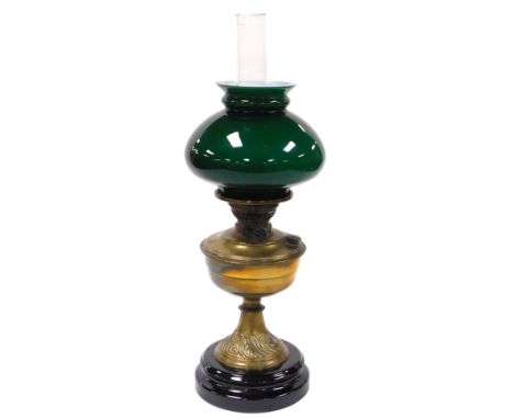 An early 20thC brass oil lamp, with a glass chimney and green glass shade, raised on a socle base, 55cm high. 