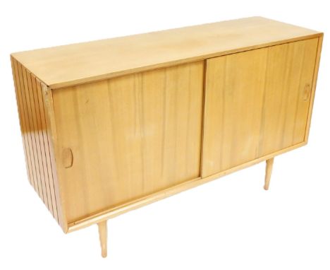 A mid century Heal's light teak sideboard, with two sliding doors enclosing shelves and a drawer, raised on turned legs, 87cm