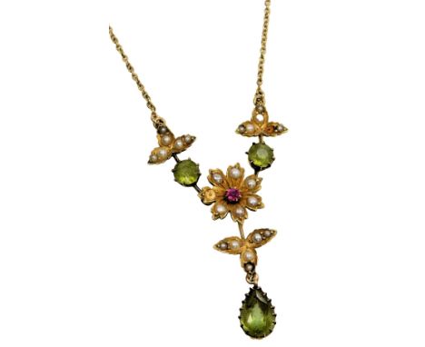 An Edwardian peridot seed pearl and ruby floral pendant, one seed pearl lacking, in yellow metal stamped 15ct, on a belcher l