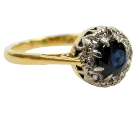 An 18ct gold sapphire and diamond ring, the circular sapphire in a surround of tiny diamonds, size L½, 3.0g.