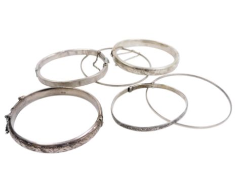 Two silver bangles, with engraved decoration, on snap clasps, with safety chains as fitted, further bangle with engine turned