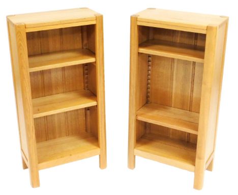 A pair of light oak bookcases, with a carved signature leaf motif to the top, each of three shelves, raised on stiles, 90cm h